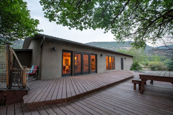 A modern house with a deck, large windows, and a view of the mountains.
