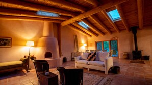 A cozy room with a fireplace, a sofa, and a dining area. - Peaceful family/group home with private attached treehouse (Canones)