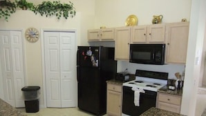 A kitchen with a granite countertop, a black refrigerator, a microwave, a stove, and wooden cabinets. - Ref 03 Luxury 4 Bed Villa With Lake View own Pool (Kissimmee)