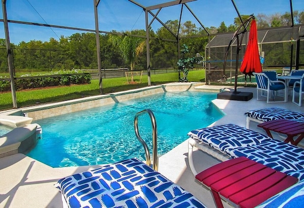 A pool area with lounge chairs and a hot tub.