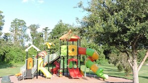 Ein Spielplatz mit Rutschen und Klettergerüsten, umgeben von Bäumen.