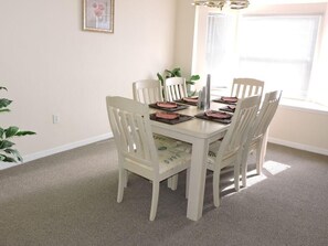 A dining area with a round table and six white chairs. - Ref 09 Luxury 4 Bed Villa With Private Pool and Lake View (Kissimmee)