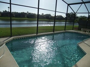A swimming pool with a view of a lake and a grassy area. - Ref 09 Luxury 4 Bed Villa With Private Pool and Lake View (Kissimmee)