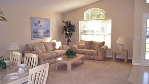 A living room with two sofas, a coffee table, and a dining table set for four. - Ref 06 Modern 4 Bed Villa With own Pool Gated Resort (Kissimmee)