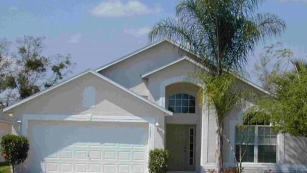 A single-story house with a garage, a front lawn, and a palm tree. - Ref 06 Modern 4 Bed Villa With own Pool Gated Resort (Kissimmee)