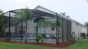 A house with a covered outdoor area, a pool, and a lawn. - Ref 06 Modern 4 Bed Villa With own Pool Gated Resort (Kissimmee)