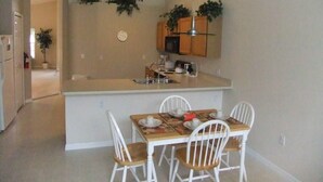 A compact kitchen with a central island, white chairs, and a dining table. - Ref 06 Modern 4 Bed Villa With own Pool Gated Resort (Kissimmee)
