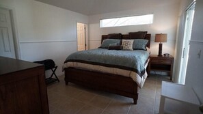 A bedroom with a large bed, a nightstand, a lamp, and a window. - Ref C Luxury 4 Bed Villa on Gated Resort Near Disney (Kissimmee)