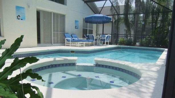 An indoor swimming pool with a hot tub, surrounded by lounge chairs and umbrellas. - Ref D Stunning 4 Bed Villa With own Pool spa Near Disney (Kissimmee)