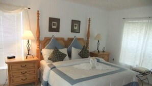 A bedroom with a large bed, two bedside tables, a nightstand, a chair, and a window with blinds. - Ref D Stunning 4 Bed Villa With own Pool spa Near Disney (Kissimmee)