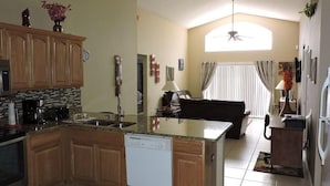 A modern kitchen with a central island, wooden cabinets, and a dishwasher. - Ref E Luxury 4 Bed Villa With Private Pool Near Disney (Kissimmee)