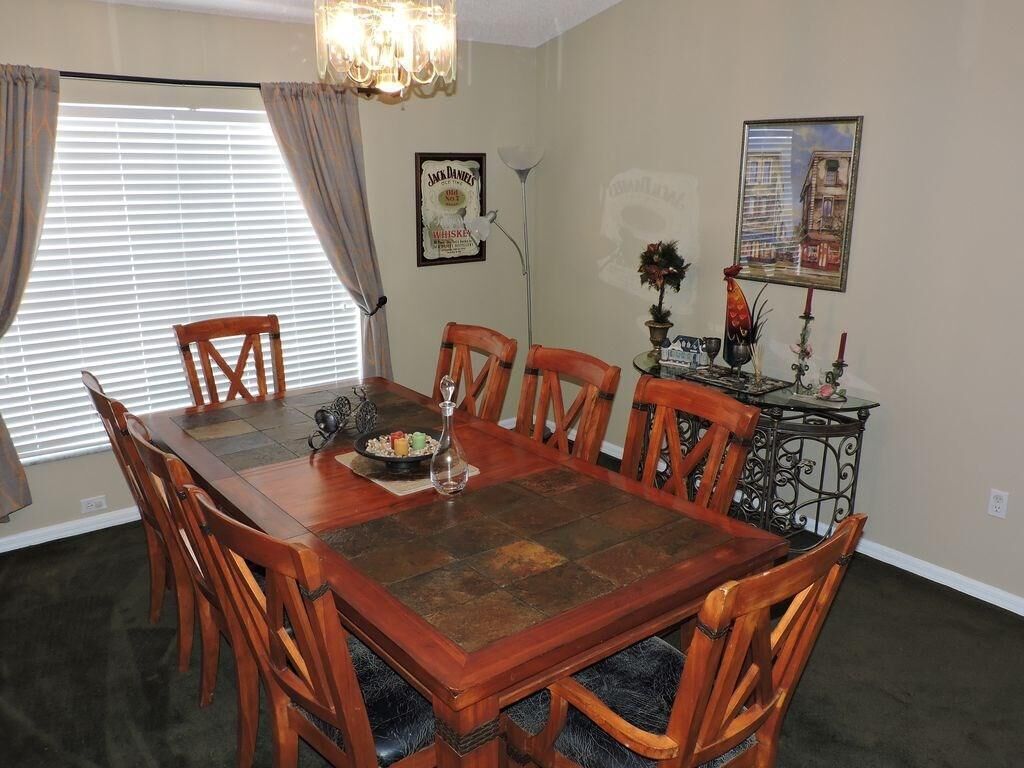 Une salle à manger avec une table et des chaises en bois, un lustre et un tableau encadré au mur.