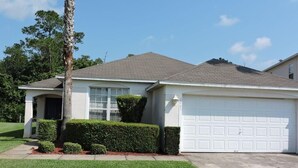 A single-story house with a garage, a well-maintained lawn, and a tall palm tree.
