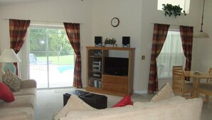A living room with a sofa, a TV stand, and a dining area with a table and chairs.