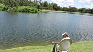 Una persona sentada en una silla junto a un lago, pescando.