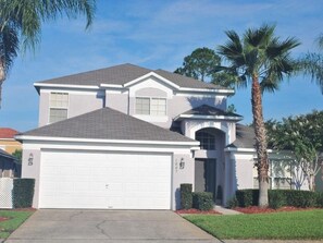 A two-story house with a white garage door, a small attached garage, and a well-maintained lawn.