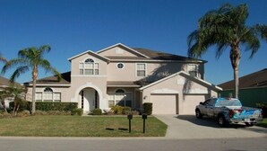 A two-story house with a garage, a driveway, and a parked truck.