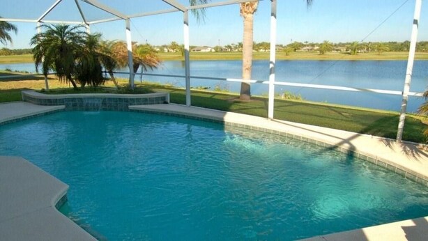 A swimming pool with a view of a lake and palm trees.