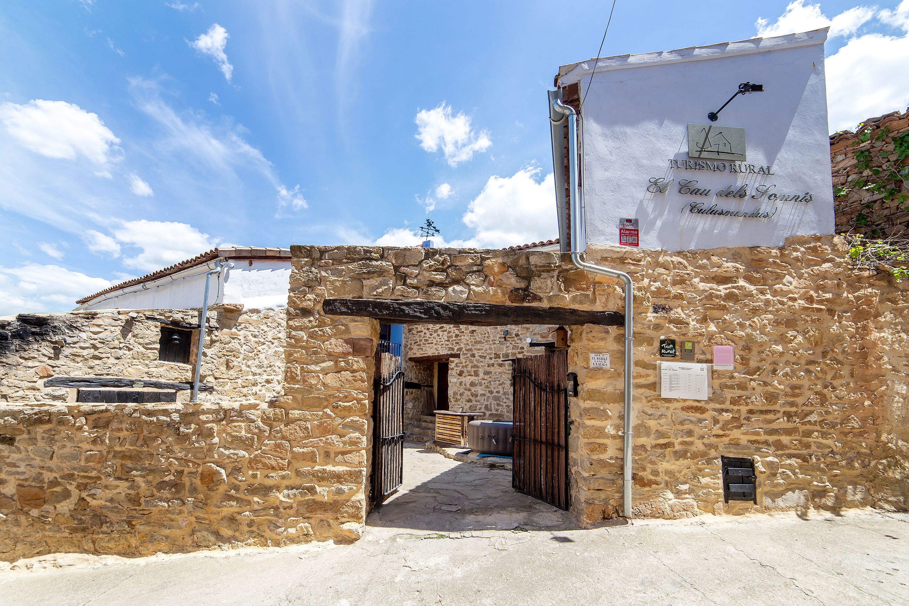 Edificio de piedra con un letrero que dice 'Turin Rural El Cau del Fornís' y una reja de metal.