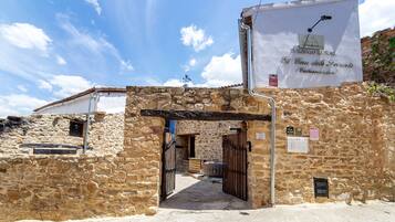 Edificio de piedra con un letrero que dice 'Turin Rural El Cau del Fornís' y una reja de metal.