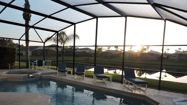 A covered swimming pool with lounge chairs and a view of a residential area. - Ref 01 Stunning 4 Bed Villa With own Pool Spa Lake View (Kissimmee)
