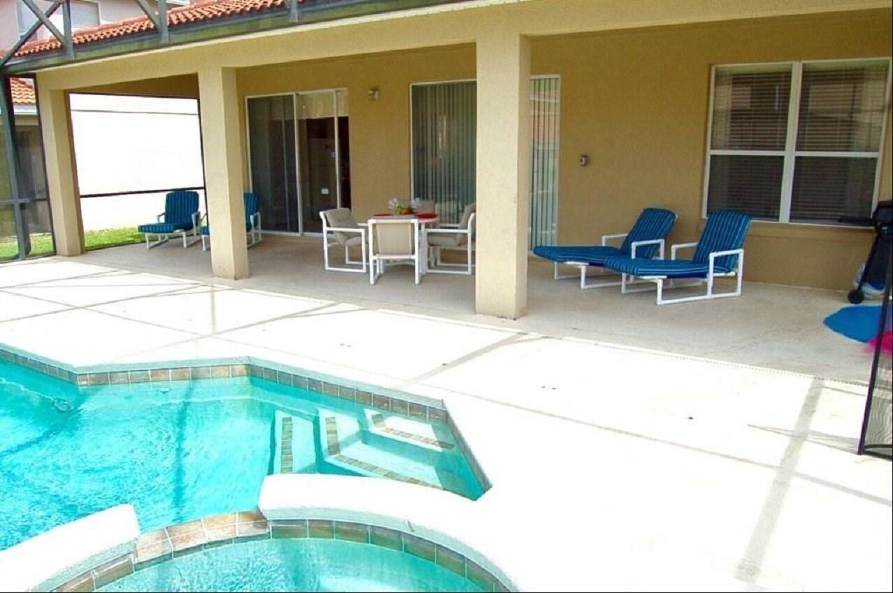 Un espace extérieur abrité avec une piscine, des chaises longues et une table.