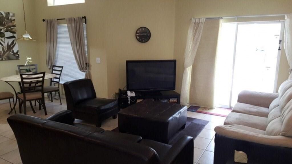 Ein Wohnzimmer mit Fernseher, Sofa und Essbereich.