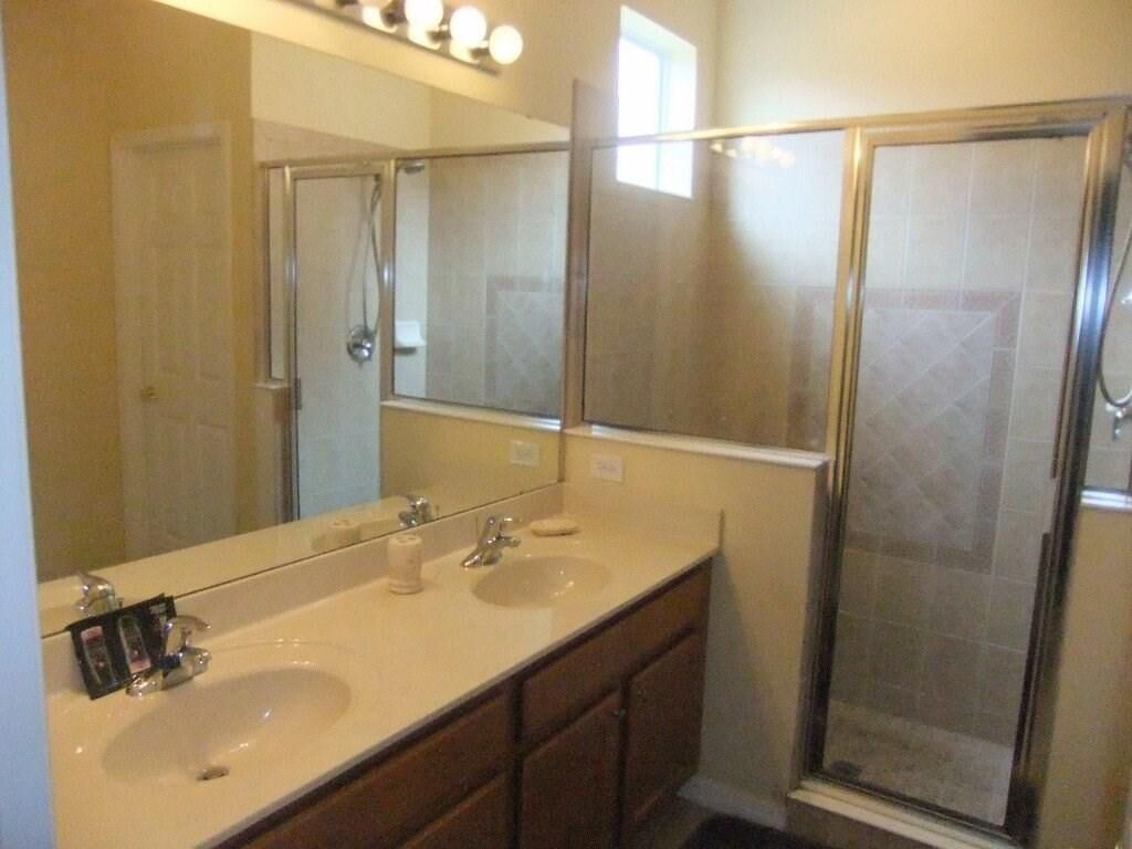 A bathroom with two sinks, a large mirror, and a glass shower enclosure.