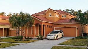 A two-story house with a red-tiled roof, a garage, and a driveway. - Ref 01bv Stunning 5 Bed 4 Bath Villa With own Pool (Kissimmee)
