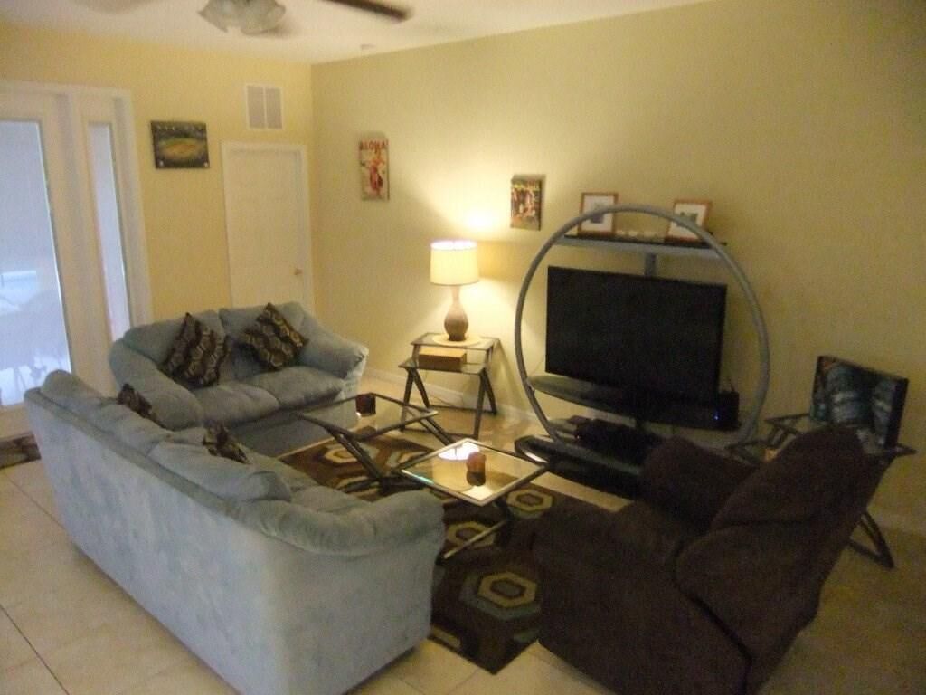 A living room with a sofa, armchair, TV, and a lamp.