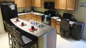 A compact kitchen with wooden cabinets, a black refrigerator, a microwave, and a coffee maker. - Ref 01bv Stunning 5 Bed 4 Bath Villa With own Pool (Kissimmee)
