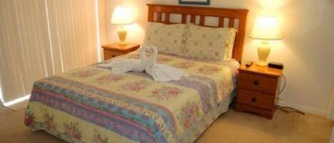 A neatly made bed with floral bedding, two bedside lamps, and a wooden headboard.