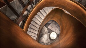 Una escalera de caracol con barandilla de madera y una taza de café al pie.
