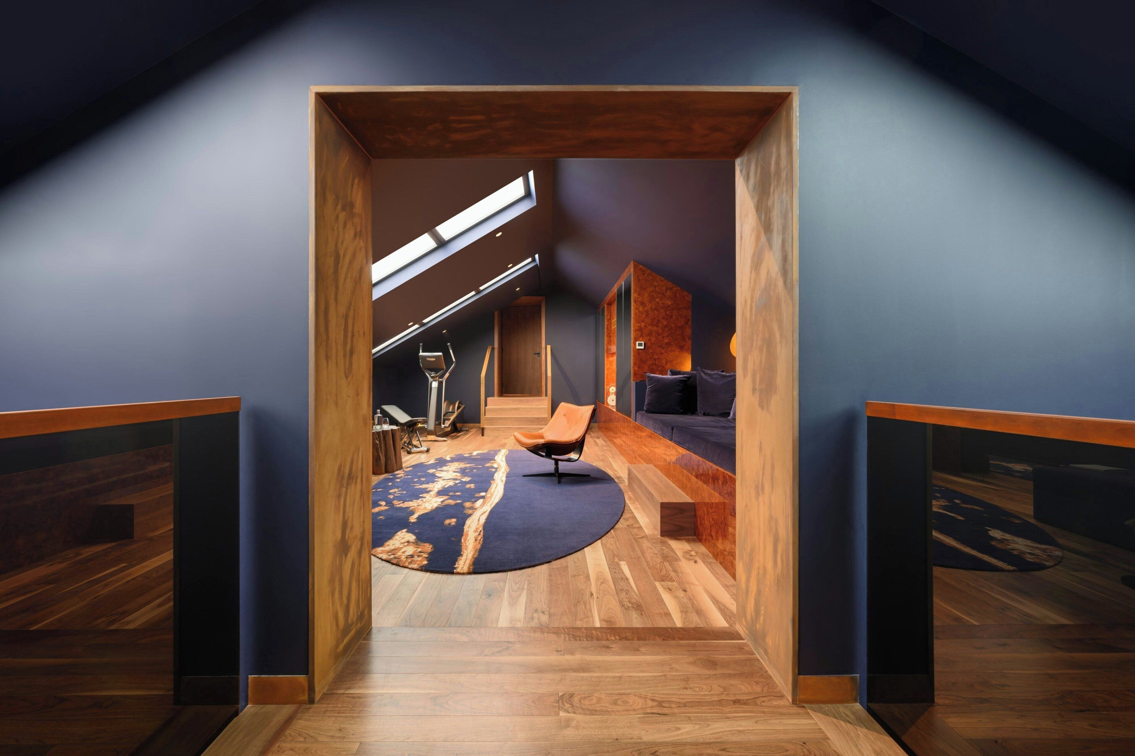 A modern interior with a wooden floor, a blue carpet, and a seating area with a sofa and a chair.