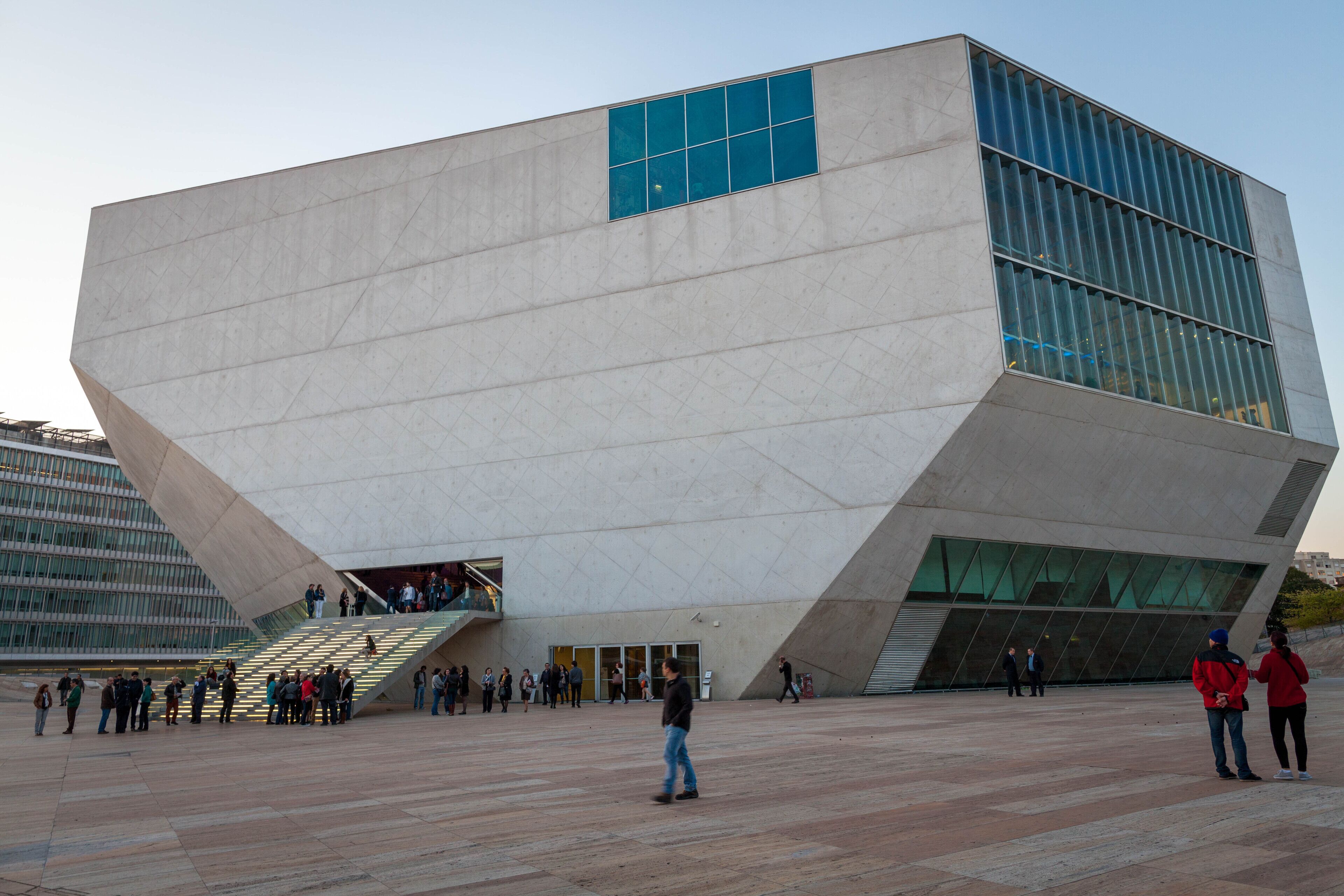 Ein modernes Gebäude mit einem einzigartigen, kantigen Design, das eine große Glasfassade und eine markante Treppe zum Eingang zeigt.