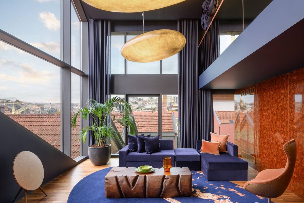Un salon moderne avec une grande fenêtre, un ensemble de canapés, une table basse et une plante en pot.