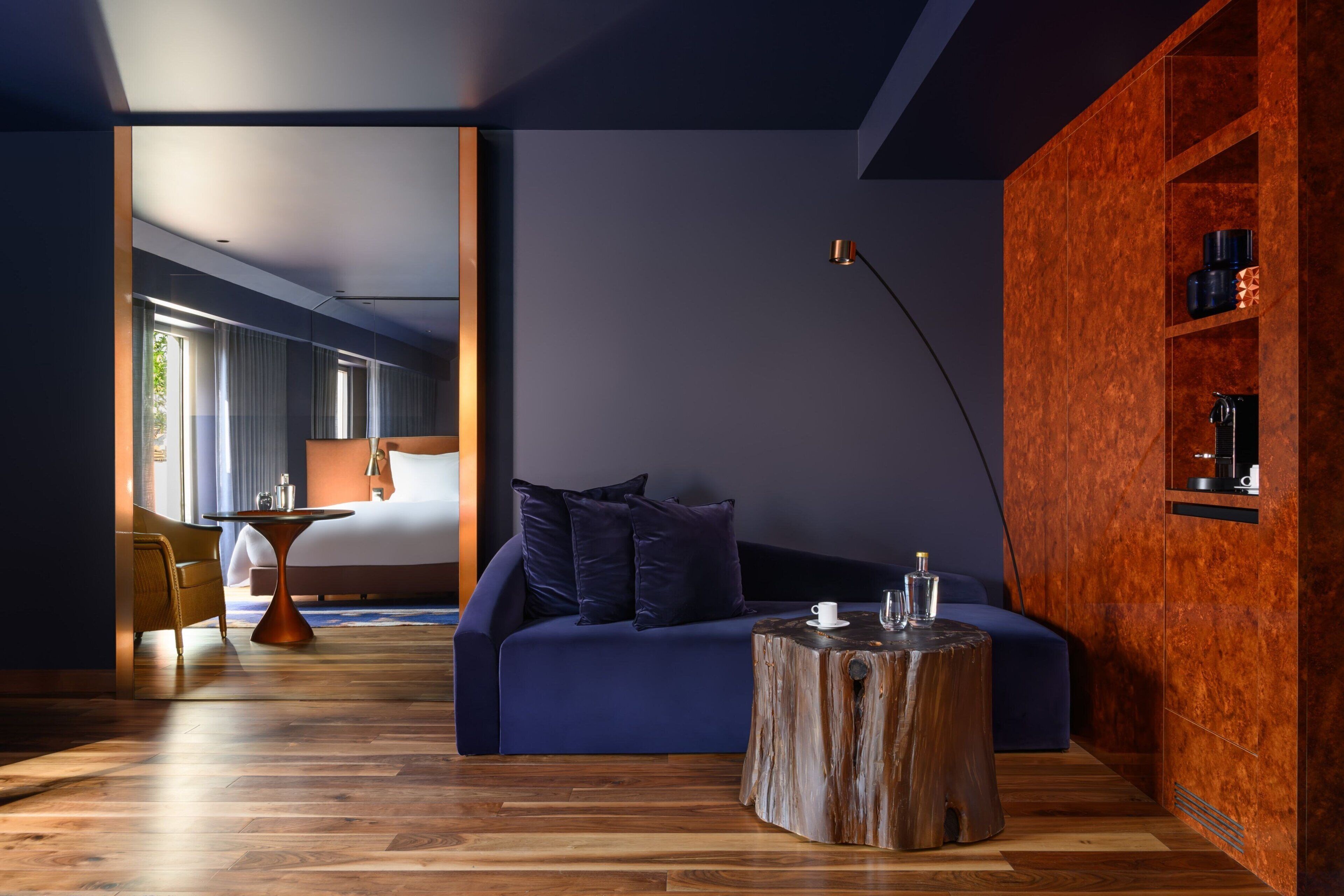 Ein modernes Zimmer mit einem blauen Sofa, einem Holztisch und einem großen Fenster.