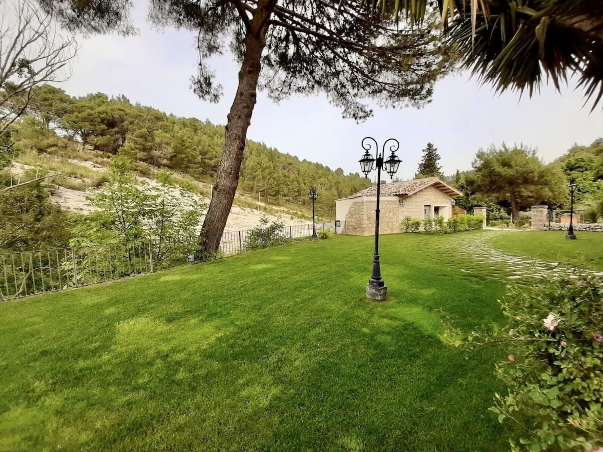 Une zone verdoyante bien entretenue, avec un bâtiment en pierre et un lampadaire.