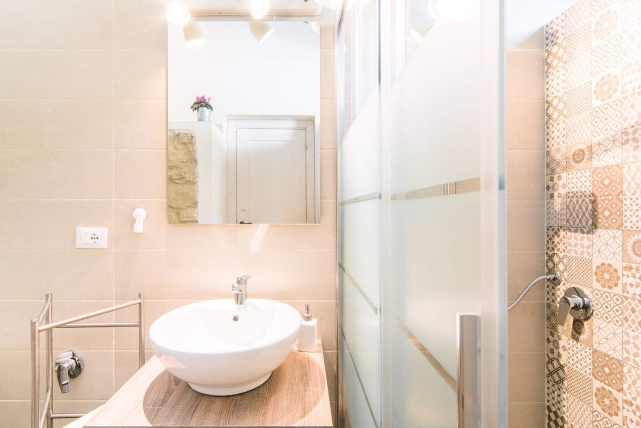 Une salle de bain avec un lavabo blanc, un miroir et un espace douche.