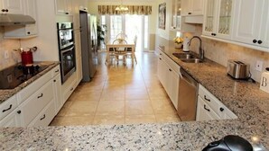 Una cocina amplia con armarios blancos, encimeras de granito y una isla central.