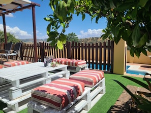 Um pátio com área de estar externa, piscina e vista para as colinas.