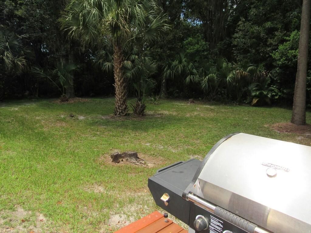 Un barbecue installé dans un espace extérieur verdoyant, avec des arbres en arrière-plan.