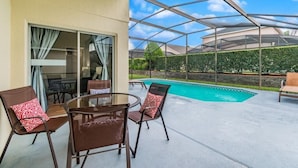 A covered outdoor area with a pool, seating, and a glass door leading to a room. - Ref 16 Stunning 4 Bed Villa on 5 Star Resort Near Disney (Kissimmee)