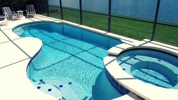 A swimming pool with a hot tub, surrounded by a deck with lounge chairs. - Ref 17 Beautiful 4 Bed Villa With own Poolspa Near Disney (Kissimmee)