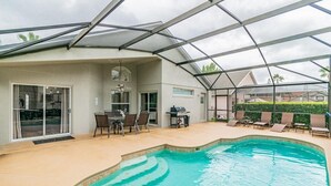 Une piscine extérieure couverte avec un espace patio, des sièges et un barbecue.
