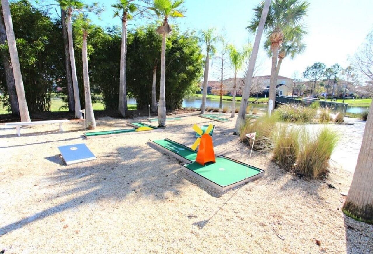 A miniature golf course with a green putting green, a yellow and orange pin, and a blue flag.