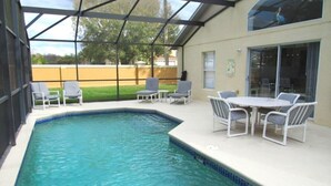 A swimming pool with a glass enclosure, surrounded by white lounge chairs and a table. - Ref 28 Stunning 4 Bed Villa With own Pool on Gated Resort (Kissimmee)