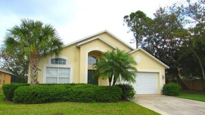 A two-story house with a garage, surrounded by well-maintained lawns and palm trees. - Ref 28 Stunning 4 Bed Villa With own Pool on Gated Resort (Kissimmee)