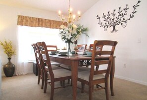 Ein Esszimmer mit Holztisch und -stühlen, einer Chandelüster und einer Wanddekoration.