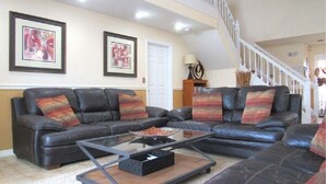 A living room with a sectional sofa, a glass coffee table, and two framed artworks on the wall. - Ref 43 Family Villa With own Pool Near Disney (Kissimmee)